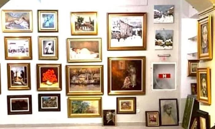 Perete de galerie cu vreo douăzeci de tablouri înrămate, așezate în rânduri și coloane aliniate
