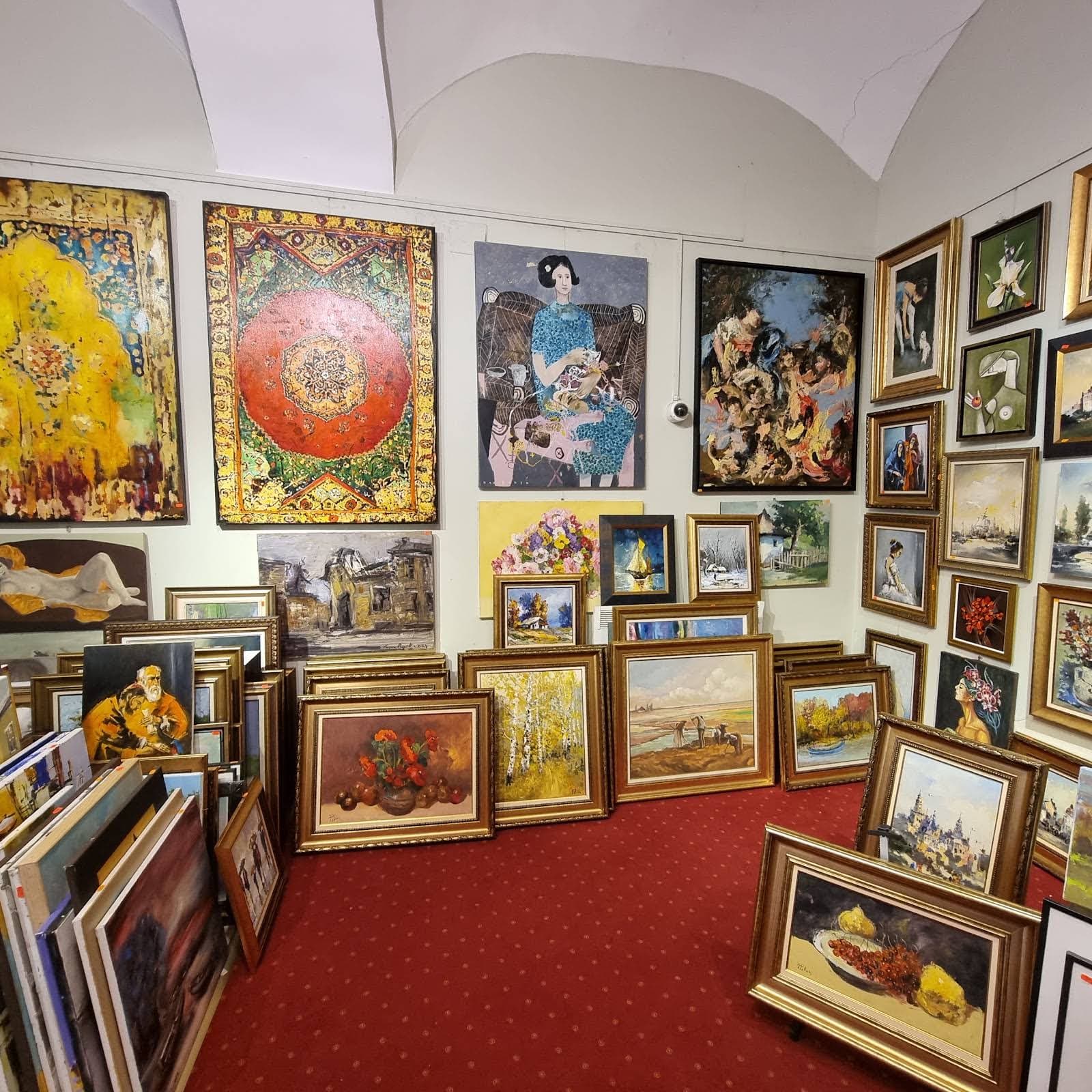 Interiorul galeriei: pereți plini de tablouri, covor roșu