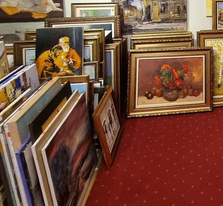 Teanc de pânze și de lucrări înrămate ținute pe muchie, una lângă alta, sprijinite de perete
